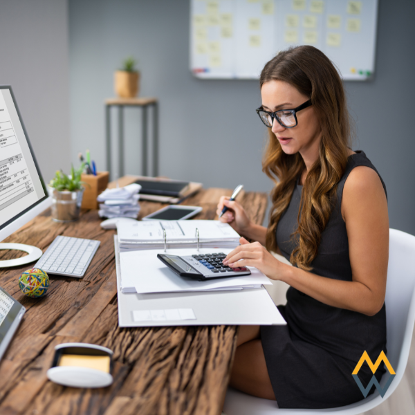 Business woman analyzing financial data with a calculator.